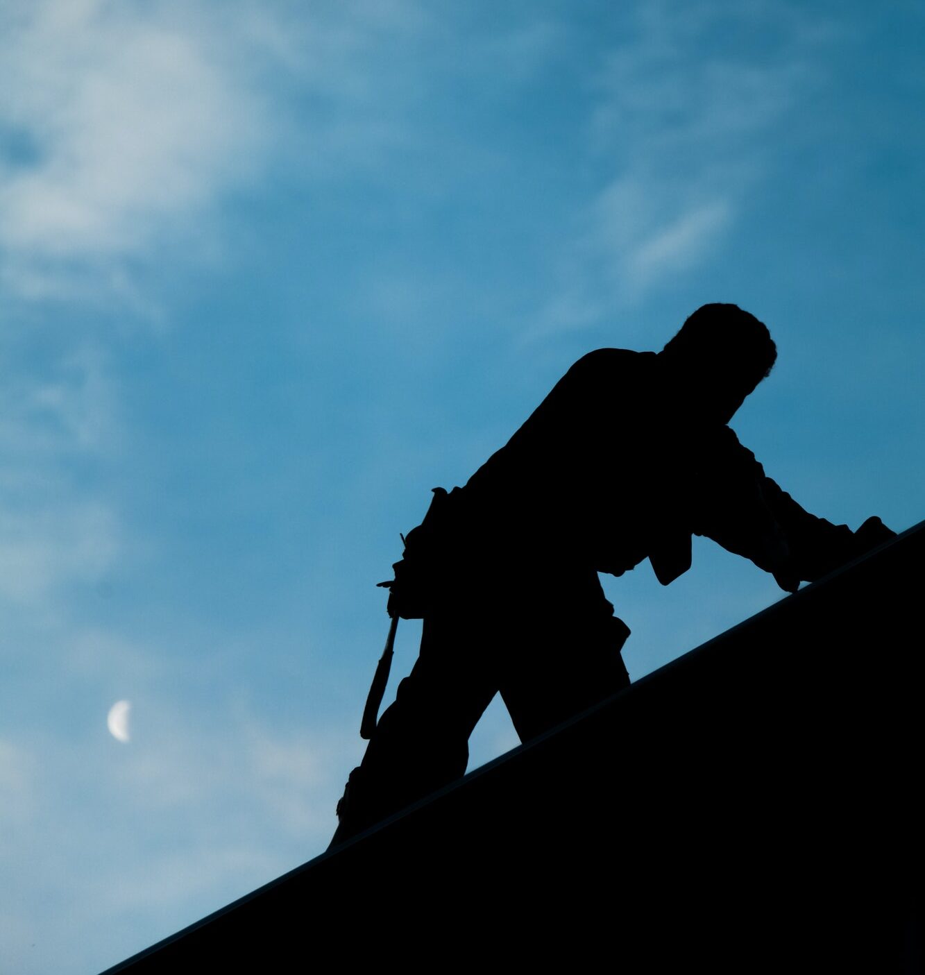 Contractor in Silhouette working on a Roof Top Contractor in Silhouette working on a Roof Top